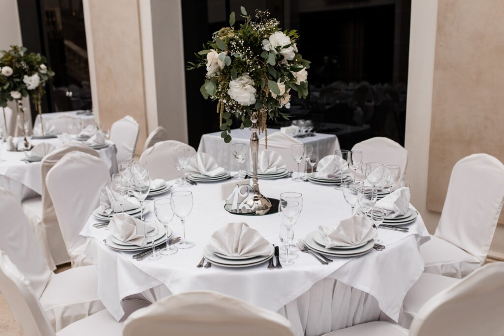 Served white round table rentals with a floral centerpiece at a restaurant.