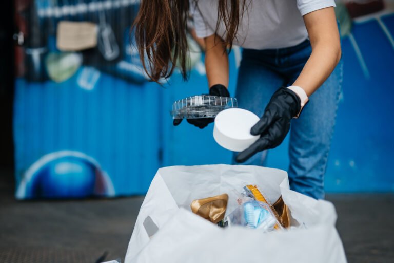 Young woman sorting garbage after BBQ with party rentals.